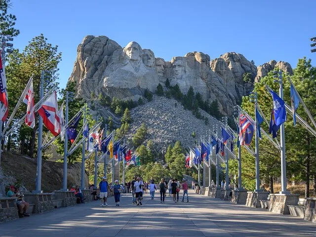 Una vista amplia del Memorial del Monte Rushmore con banderas estatales a lo largo del camino.