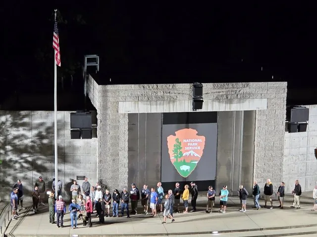 A nighttime flag-lowering ceremony at an outdoor amphitheater at Mount Rushmore.
