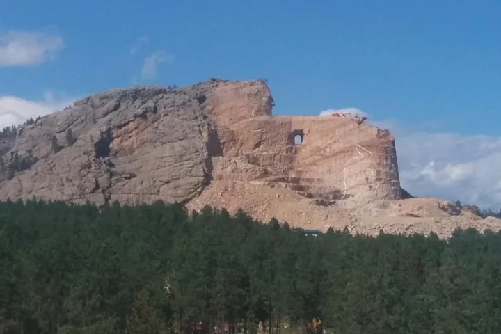 A massive, partially carved stone monument on a rocky mountain slope.